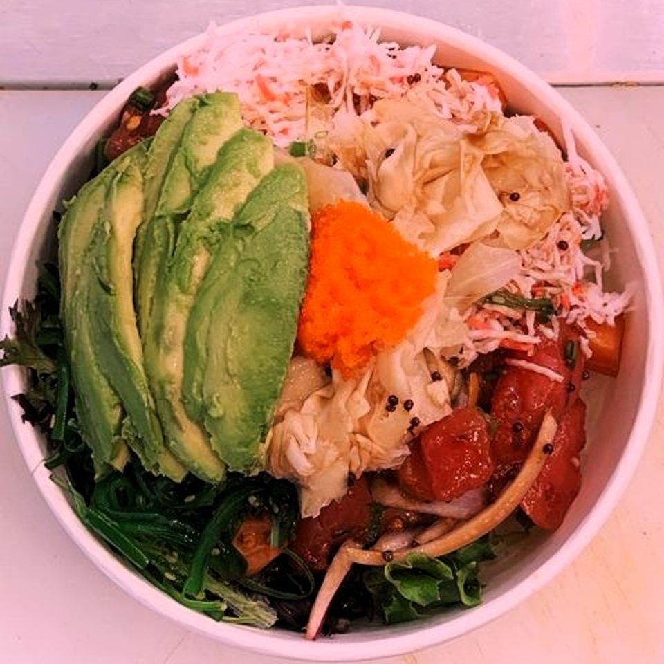 A vibrant KOKOROLL poke bowl with tuna, avocado, crab salad, seaweed, and orange tobiko.